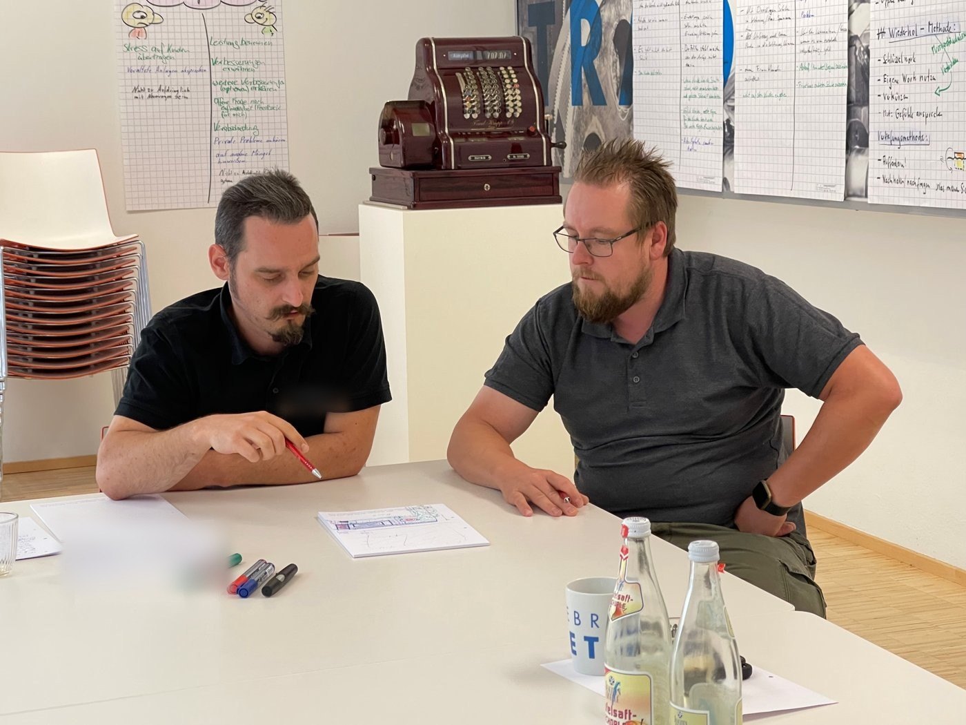 Zwei Techniker sitzen am Tisch und besprechen eine Skizze